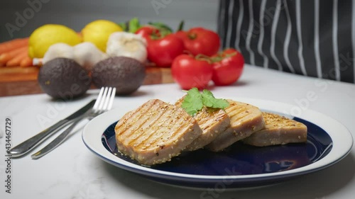 A beautiful dish of grilled yellowfin tuna steak on the table in 4K. Concept of freshly made healthy meal from tuna nicely decorated by a chef.