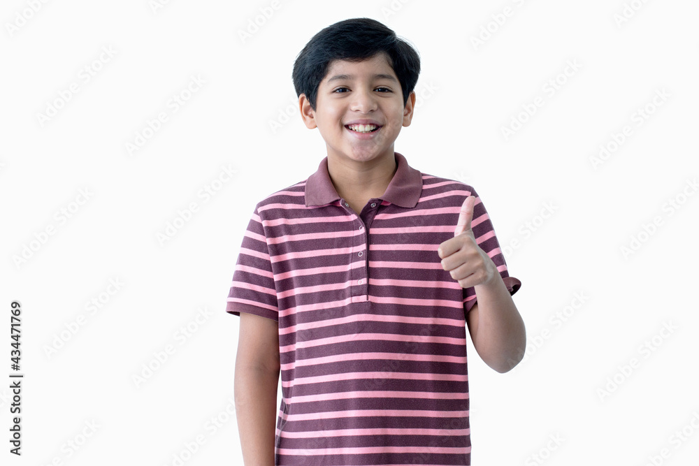 Portrait of a happy Indian boy, .shows sight thumbs up, joy and a smile, over white background and looking at camera, with clipping path Portrait of a happy Indian boy, .shows sight thumbs up, joy and a smile, over white background and looking at camera, with clipping path