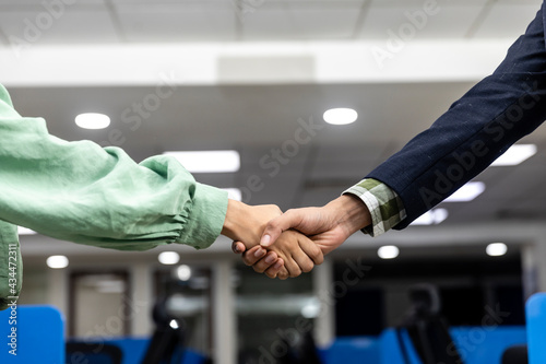 Closeup of a handshake between a businessman and businesswoman, office background, closing deal, reaching agreement, corporate environment.