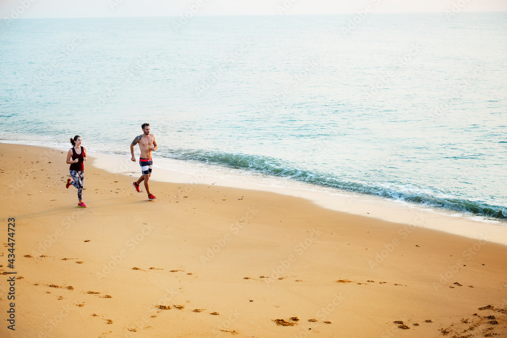 Healthy young couple running by the beach together Healthy young couple running by the beach together