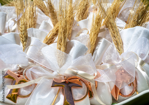 Gifts or favors for the first or holy communion. Small bags of white fabric with ear of wheat and Tau Christian cross. Religious symbol