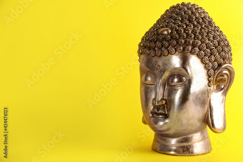Beautiful golden Buddha sculpture on yellow background. Space for text