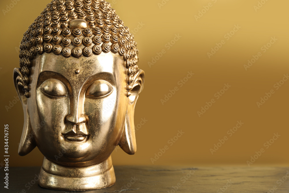 Buddha statue on table against golden background. Space for text