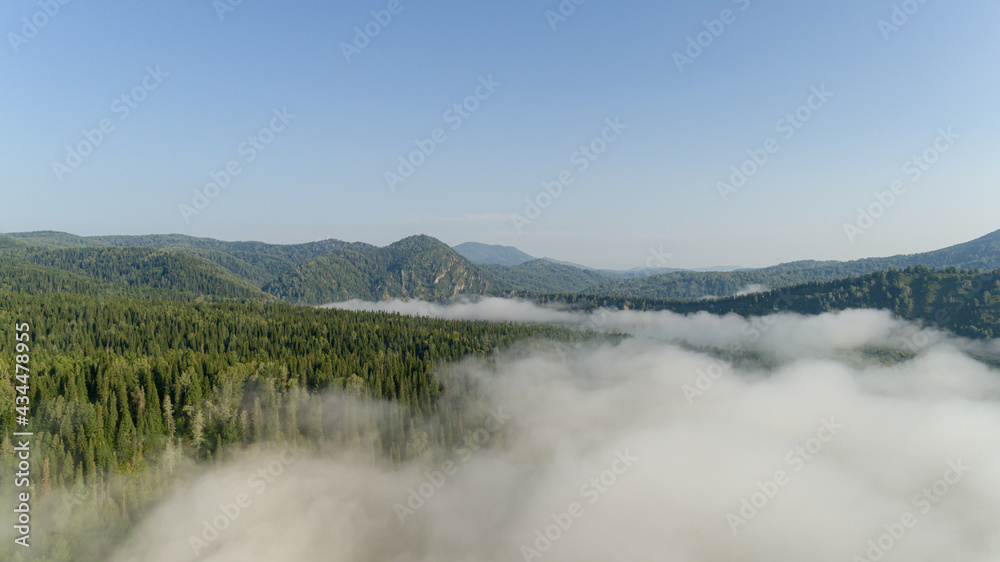 Aerial view: Amazing Sunrise and mist flowing over the mountains , Foggy morning sky with rising sun above misty siberian Natural Park 