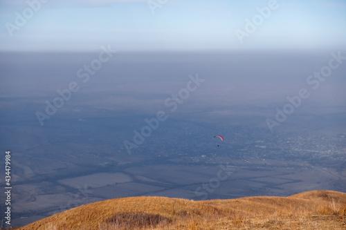 Paraglider silhouette flying on blue sky background. Nature landscape. Concept: adventure, art, travel. Blue sky background. Ushkonyr plateau, Kazakhstan. Travel in Kazakhstan concept. photo