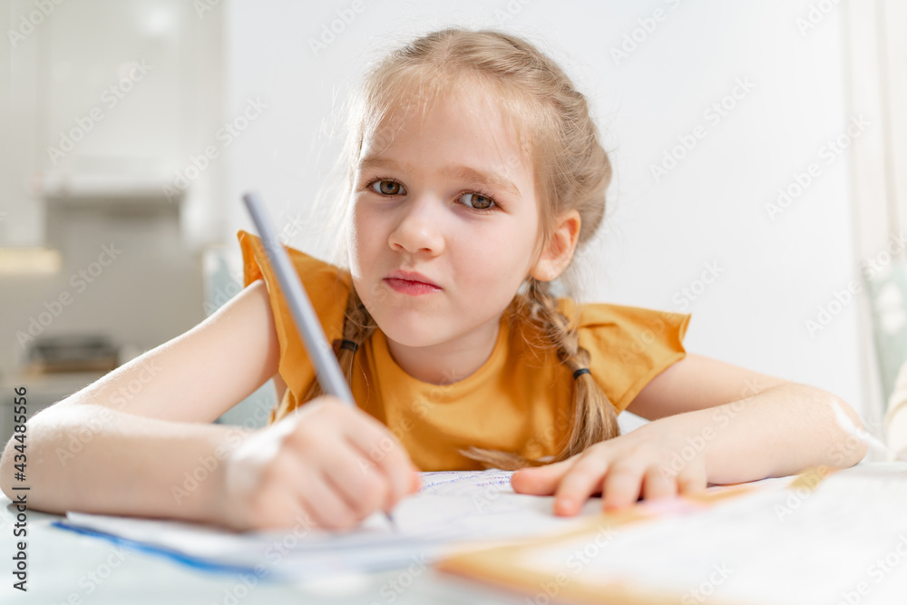 A kid schoolgirl does her homework. A kid schoolgirl does her homework.