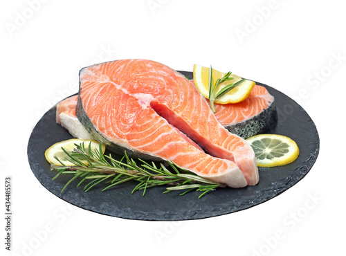 Salmon fresh fish steak served with lemon and herbs on slate isolated on white.
