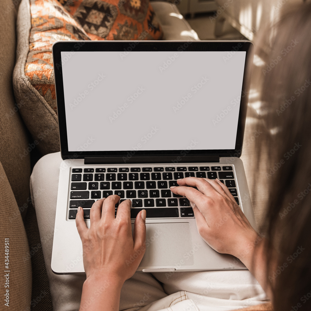 Woman working on laptop lying on the couch. Eastern traditional home interior design concept. Oriental style living room sofa, pillows. Blank copy space screen Woman working on laptop lying on the couch. Eastern traditional home interior design concept. Oriental style living room sofa, pillows. Blank copy space screen