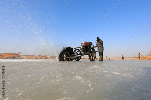 Farmers use electric saws to cut river ice in the wild. © zhang yongxin