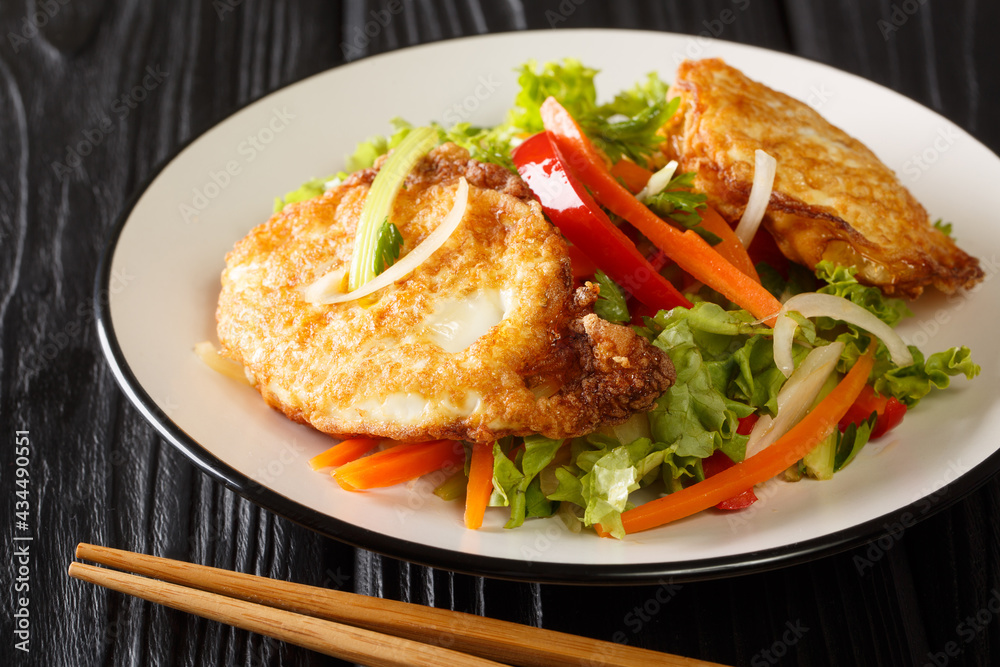 Asian salad of fried eggs with vegetables and herbs close-up in a plate on the table. horizontal Asian salad of fried eggs with vegetables and herbs close-up in a plate on the table. horizontal
