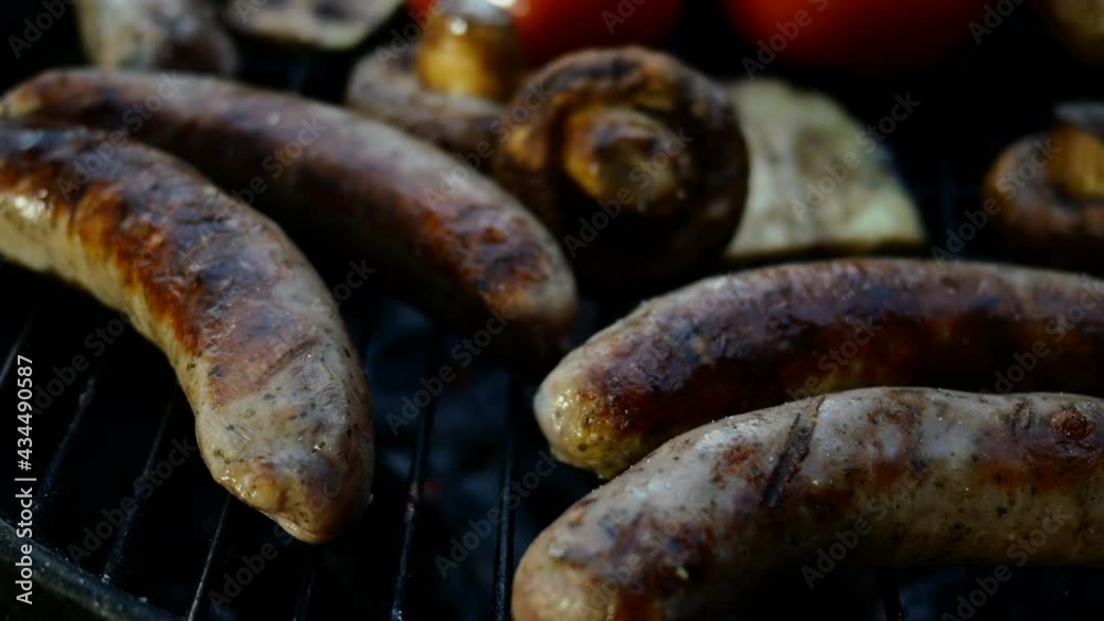 Frying fatty bavarian sausages cooked on grill or barbecue grid. With vegetables tomatoes and mushrooms. Close-up. Frying fatty bavarian sausages cooked on grill or barbecue grid. With vegetables tomatoes and mushrooms. Close-up.
