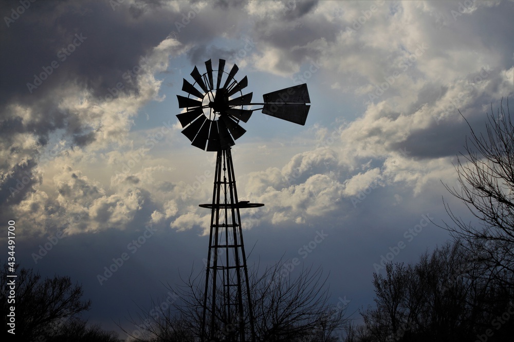 Kansas colorful Sunset with clouds and a Windmill silhouette north of Hutchinson Kansas USA out in the country. Kansas colorful Sunset with clouds and a Windmill silhouette north of Hutchinson Kansas USA out in the country.