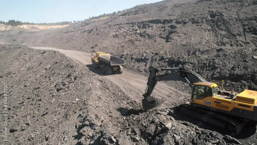 Large quarry dump truck. Loading rock in dumper. Loading coal into truck. Mining car machinery to transport coal. Open pit mine quarrying extractive industry stripping work. Big Yellow Mining Trucks Large quarry dump truck. Loading rock in dumper. Loading coal into truck. Mining car machinery to transport coal. Open pit mine quarrying extractive industry stripping work. Big Yellow Mining Trucks