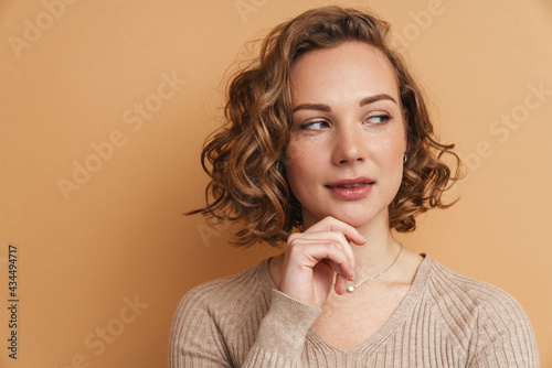 Young ginger woman with wavy hair posing and looking aside