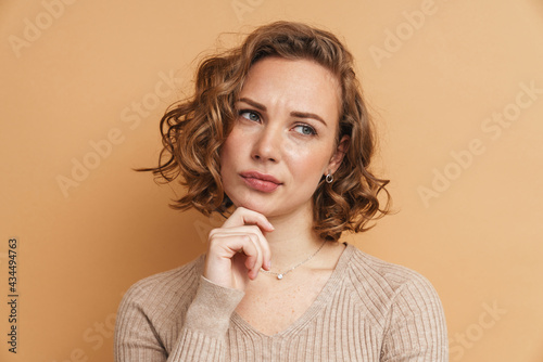 Young ginger puzzled woman frowning and looking aside