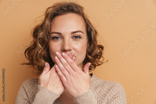 Young ginger woman looking at camera while covering her mouth