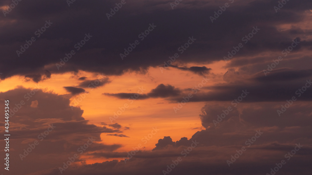 Beautiful orange sunset sky with layers of gray and dark clouds. Scenic view. Beauty in nature. Twilight sky. Heaven sky at dusk for tranquil and peaceful background. Romantic sunset sky.