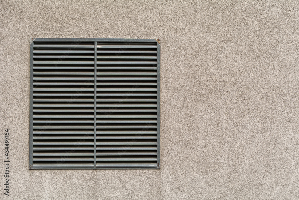 Metal ventilation outlet on a house wall with air slits. Wall background with copy space for text