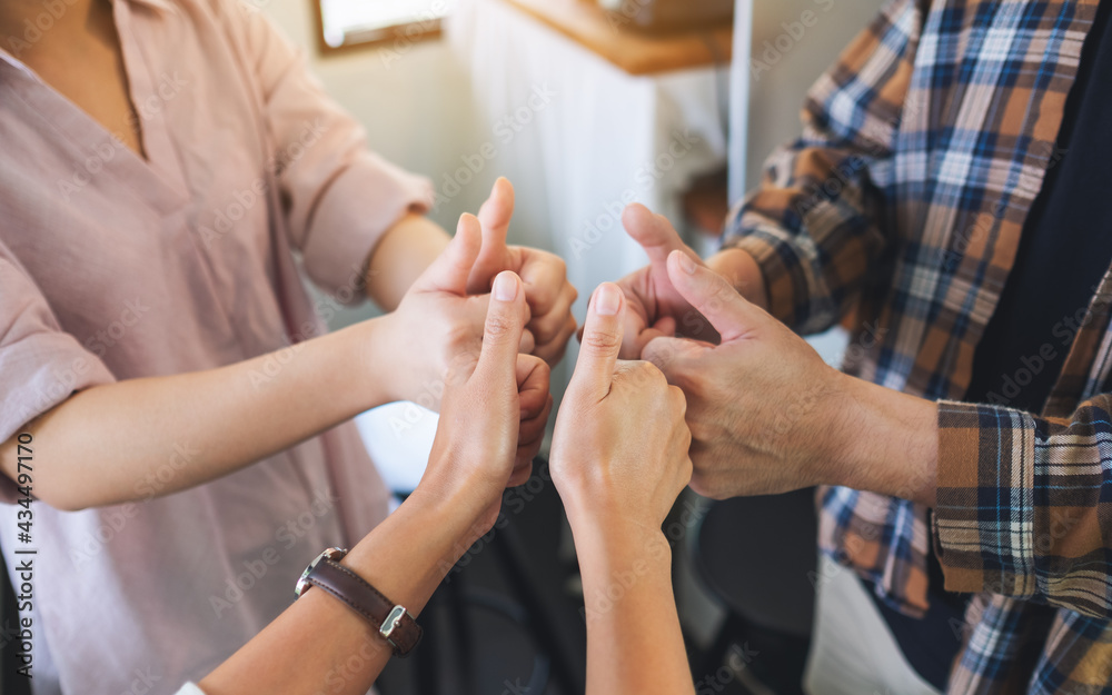 A group of people making thumbs up hands sign in circle