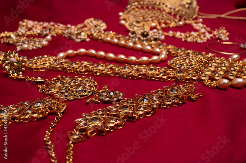 Indian traditional gold Indian wedding women's jewelry on red saree background. Close-up. Still-life.