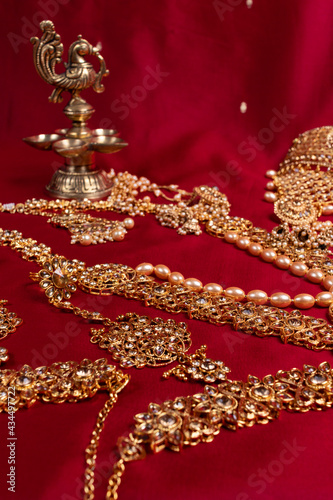 Indian traditional bronze oil lamp in the shape of a bird and gold Indian female jewelry on the red saree background. traditional Indian religious ceremony of Hindus. Diwali