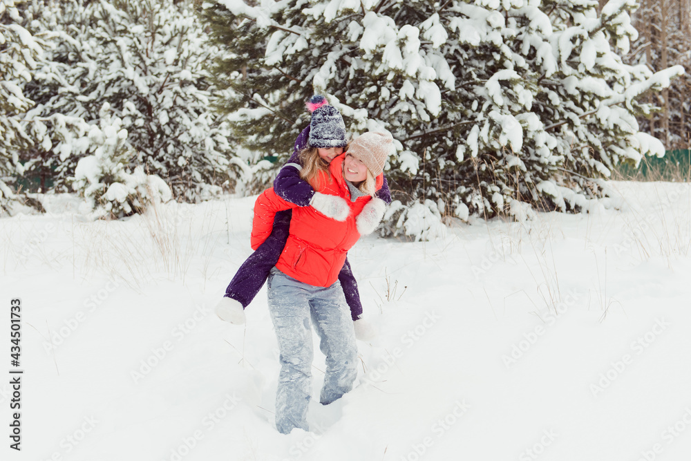 mother Carrying daughter Piggyback Having Fun In Winter Forest mother Carrying daughter Piggyback Having Fun In Winter Forest