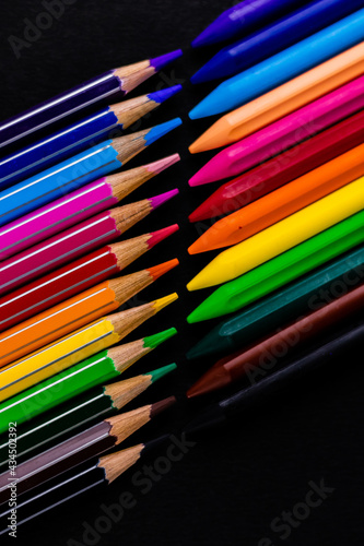 Portrait mode top close up shot of color pencils and crayons points facing each other - fun learning and drawing concept.