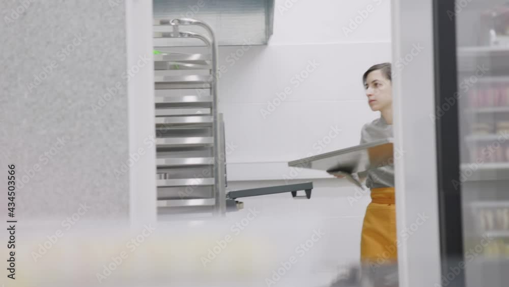 The pastry chef checks the readiness of the dish in the oven The pastry chef checks the readiness of the dish in the oven