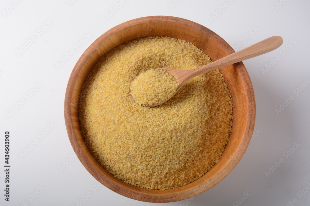 Uncooked bulgur in wooden bowl on white table background, rustic style. Bulgur wheat grains Uncooked bulgur in wooden bowl on white table background, rustic style. Bulgur wheat grains