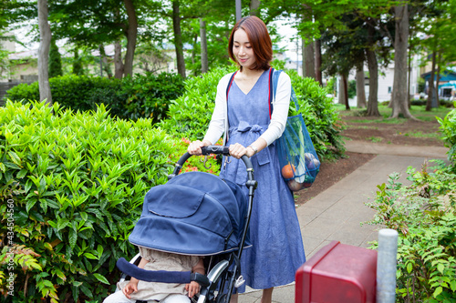 公園をベビーカーを押して歩く、妊娠中のお母さん photo