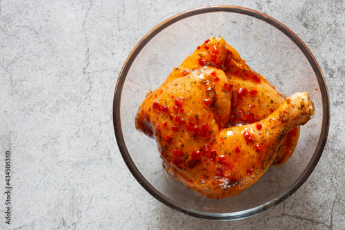 Chicken with a piri or peri marinade sauce in a glass bowl.  On a concrete background photo