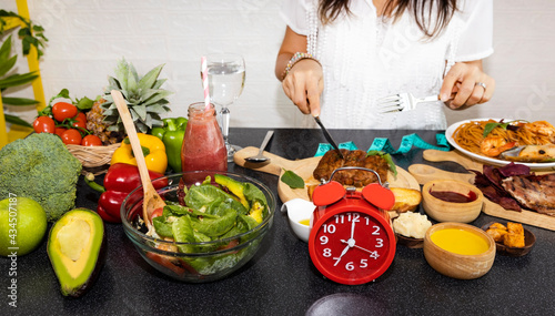 Selective focus of Red clock and organic chipotle pork which young woman  she is Intermittent fasting eating salad  and healthy food  lifestyle concept image photo