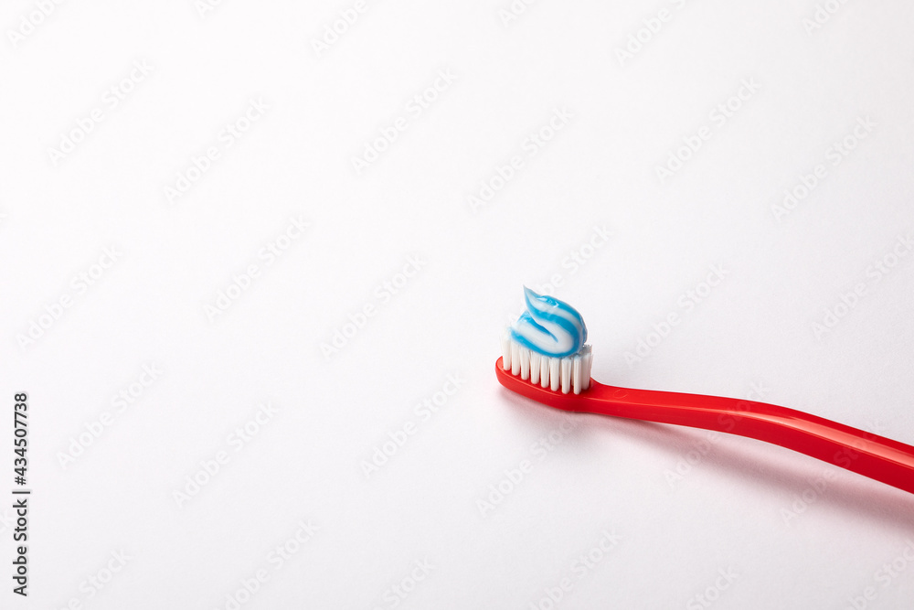 Toothpaste on a red toothbrush. White background with space for text and information Toothpaste on a red toothbrush. White background with space for text and information