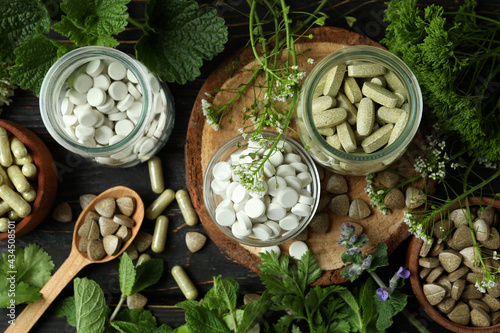 Concept of herbal medicine pills on wooden table, top view