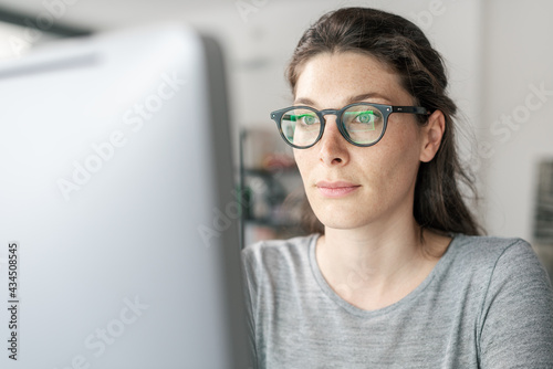 Woman with glasses working on a computer photo