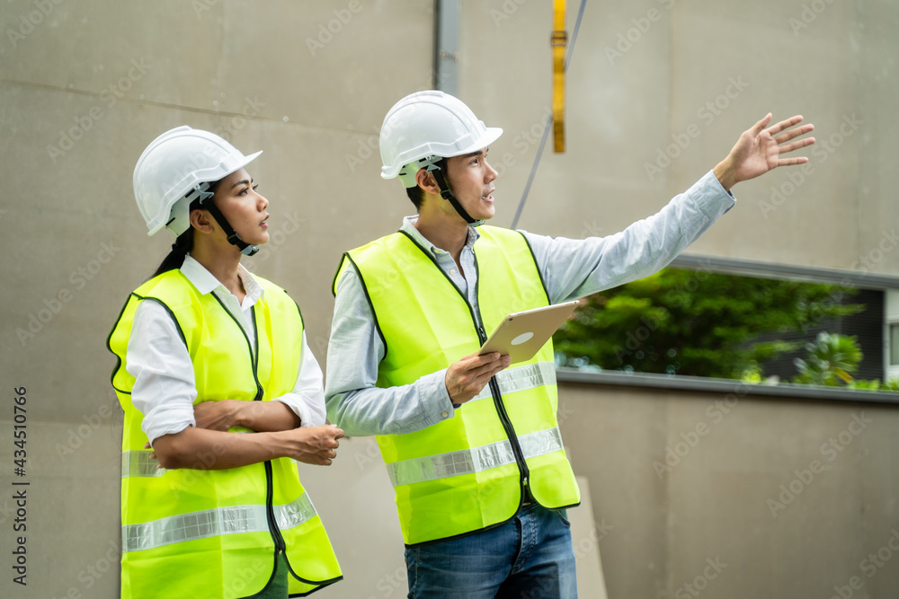 Asian male architect explaining job on tablet to his colleague on site Asian male architect explaining job on tablet to his colleague on site