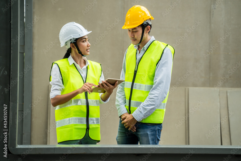 Asian female engineer explaining job on tablet to her worker on site. Asian female engineer explaining job on tablet to her worker on site.