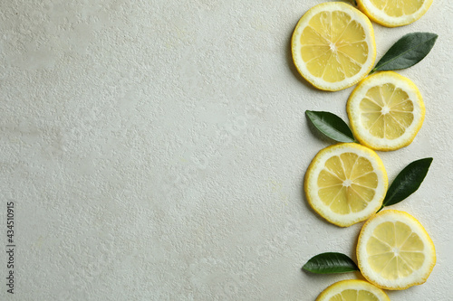Lemon slices and leaves on white textured background, space for text