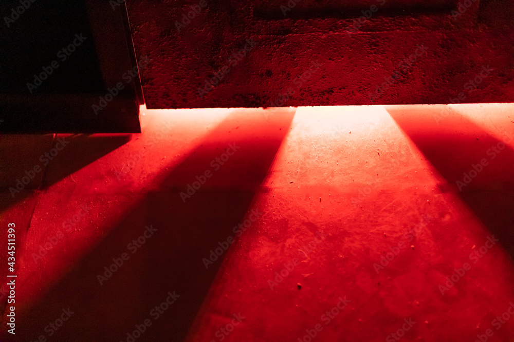 A mystical and dangerous red light through a gap under the door. Fabulous atmosphere of mysteries and horrors for decor - obrazy, fototapety, plakaty 