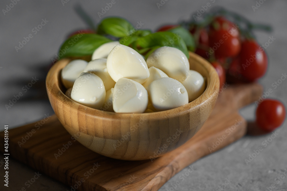 close up of fresh apulian mozzarella cheese in a wooden bowl with fresh leaf of basil, close up and selective focus, food made in Puglia, Italy close up of fresh apulian mozzarella cheese in a wooden bowl with fresh leaf of basil, close up and selective focus, food made in Puglia, Italy