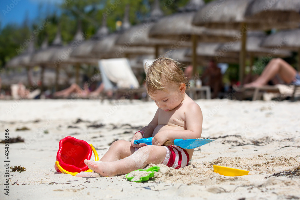 Cute baby boy playing with beach toys on tropical beach Cute baby boy playing with beach toys on tropical beach