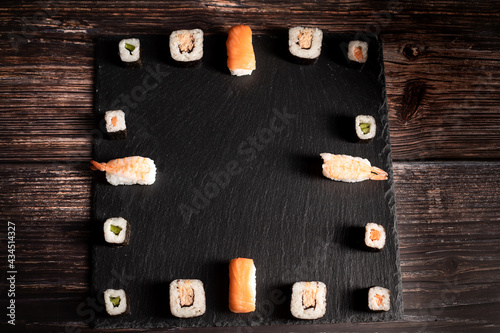 Sushi und Garnelen liegen auf dem schwarzen Brett, In der Mitte ist viel Platz zum schreiben. Die Sushi ist aufgeteilt wie die Zahlen einer Uhr. Japanische Restaurant, Asiatische Küche. photo