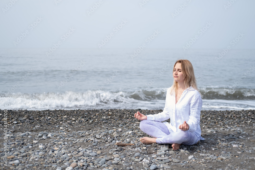Young women practicing yoga at beach in meditation pose