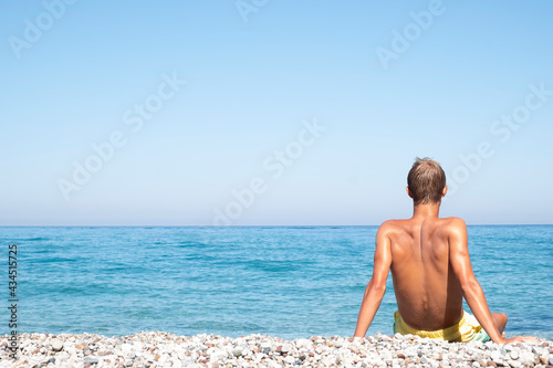 The man sits on the seashore. Summer vacation concept. Copy space