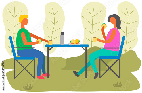 Urban park visitors drink coffee at table. Young man and woman are sitting in outdoor cafe and drinking hot beverage. People in relationship communicate on date together during cold weather