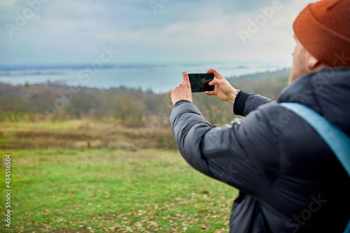 Traveler man with backpack makes photos or selfie on a smartphone