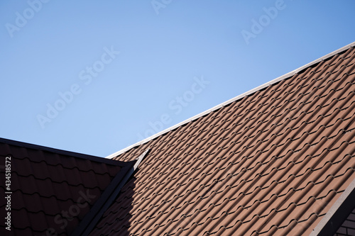 Brown corrugated metal profile roof installed on a modern house. The roof of corrugated sheet. Roofing of metal profile wavy shape. Modern roof made of metal. Metal roofing.