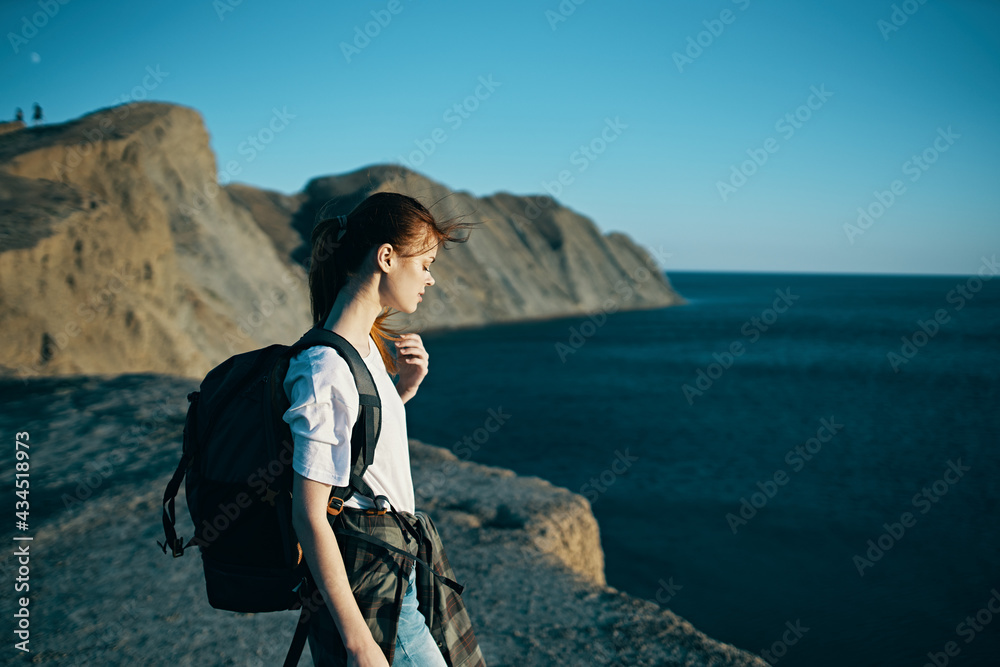 Fototapeta premium woman with backpack travels in the mountains near the sea