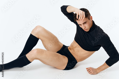 a guy in a sweater shorts and socks lies on the floor on a light background in full growth model
