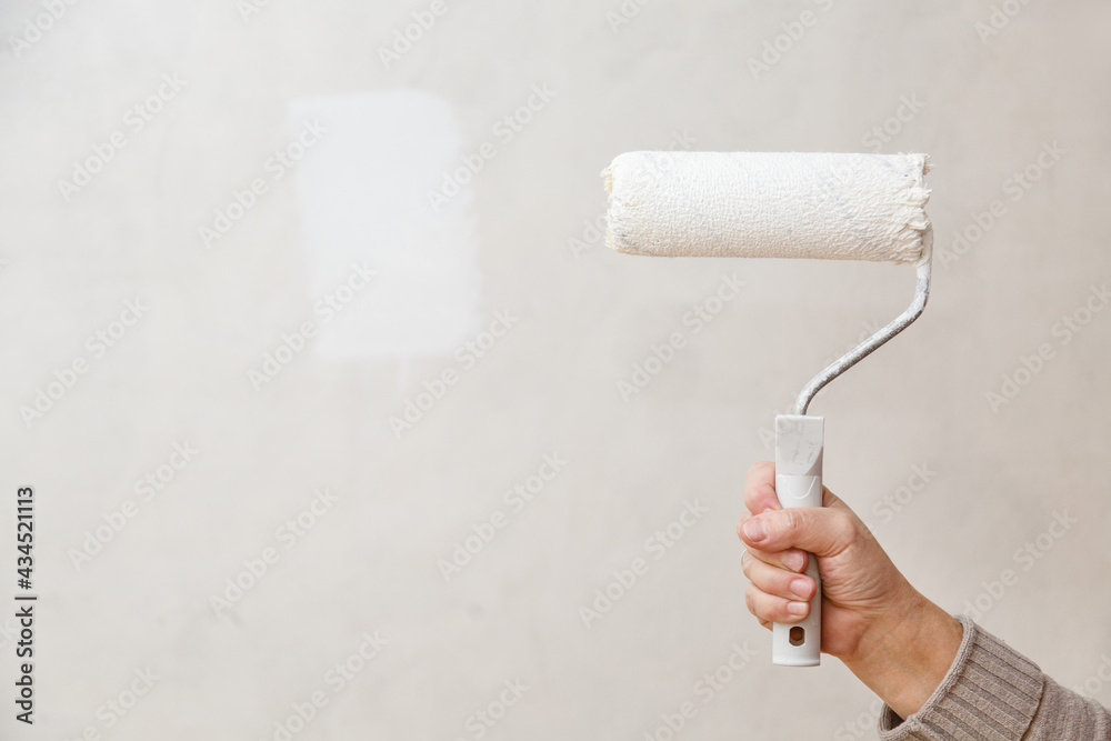Obraz premium Painting roller in worker's hand. Repair in a room. Painting of walls